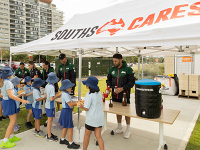 Young students lining up at a barbecue hosted by Souths Cares and Randwick Council