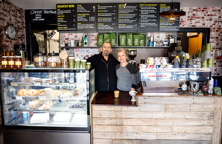Melissa and Carlos run a cafe and crystal business. Cafe owners Melissa and Carlos standing behind the counter at their buisness Carmelos Cafe