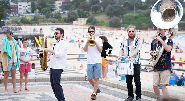 Four musicians from Oompah loompah playing music at Coogee Beach in front of crowd