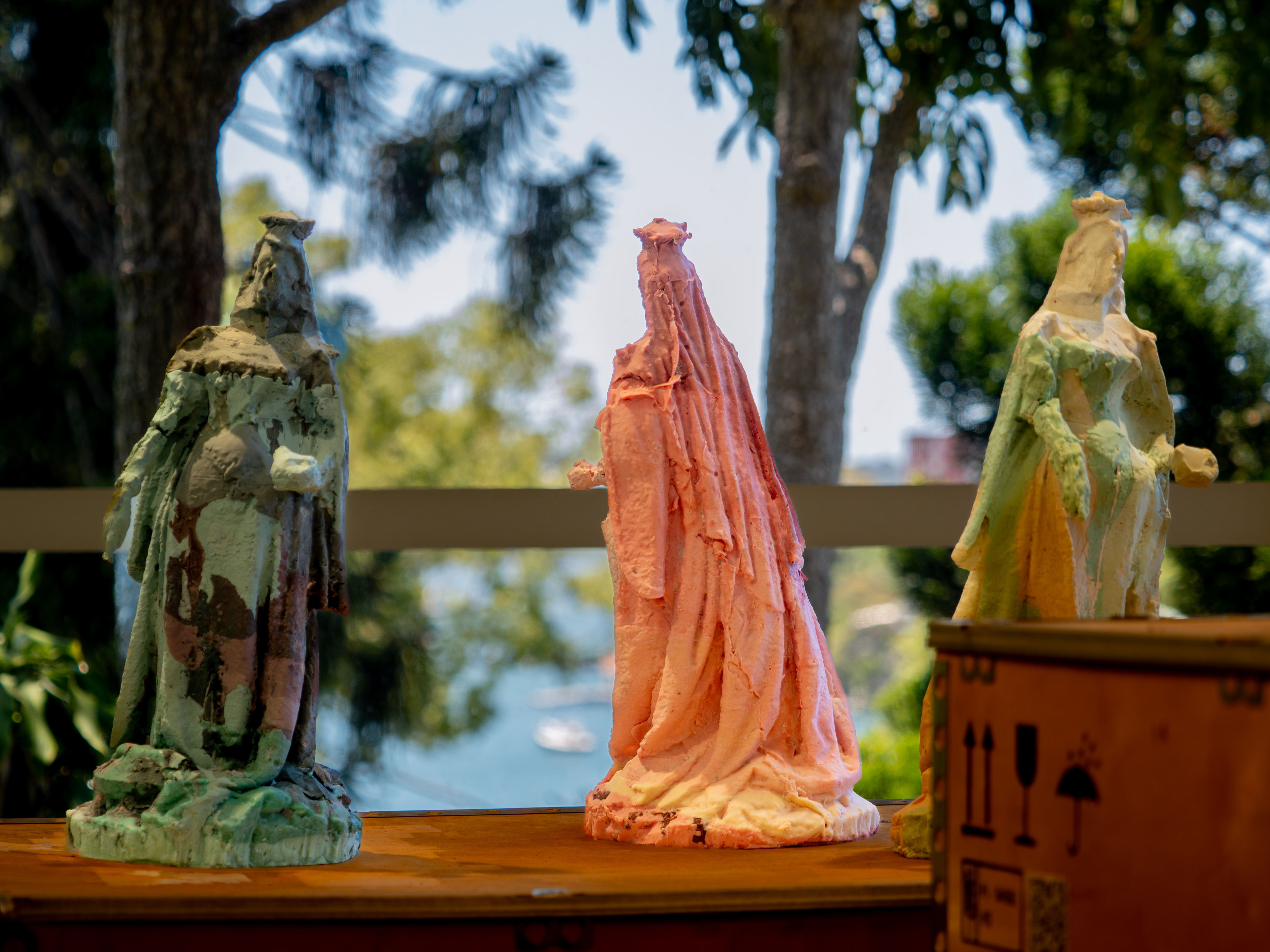 Three wax sculptures of Queen Victoria set against a garden background