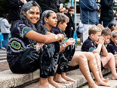 A group of school children sitting on the steps at Coogee Beach, awaiting Koojay Corroboree