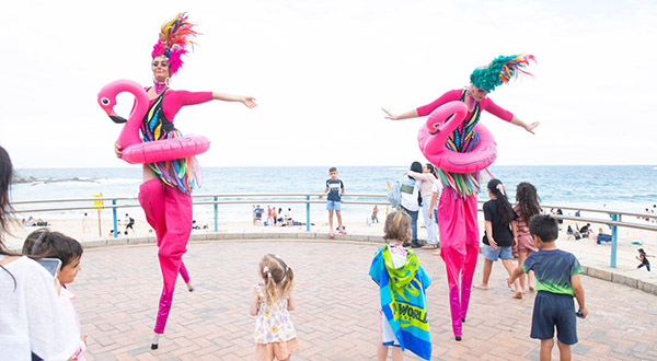 Two roving entertainers dressed as pink flamingos on high stilts
