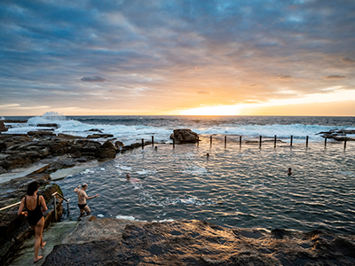 Mahon Pool, with some swimmers climbing into it, and the sun hitting the water