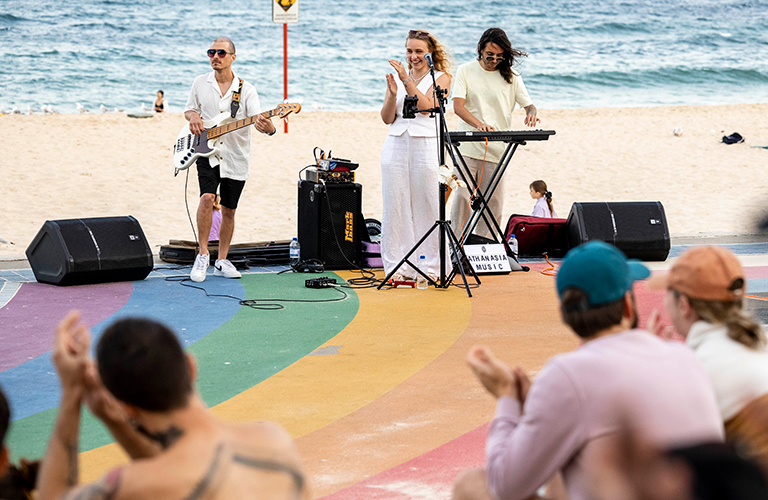 A photo of musicians performing to an audience on the Rainbow Walkway at Coogee Beach.